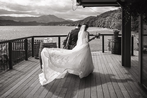 bride's dress blows in the wind as she walks around a corner